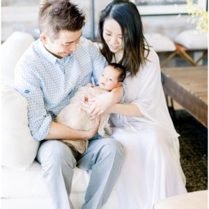 A couple holding their newborn while sitting on a couch