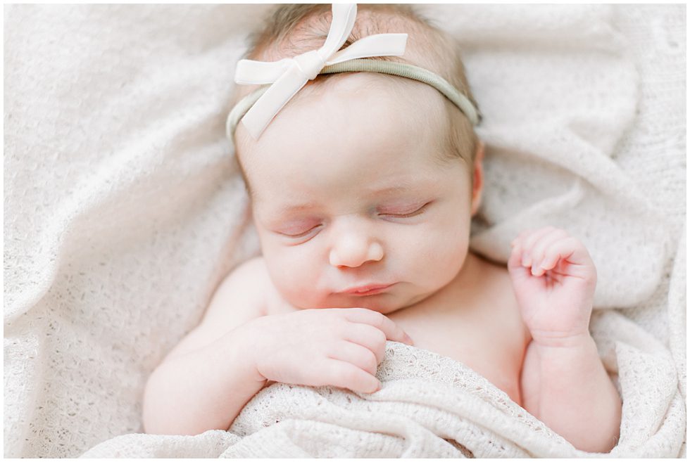 A newborn wearing a thin headband and sleeping